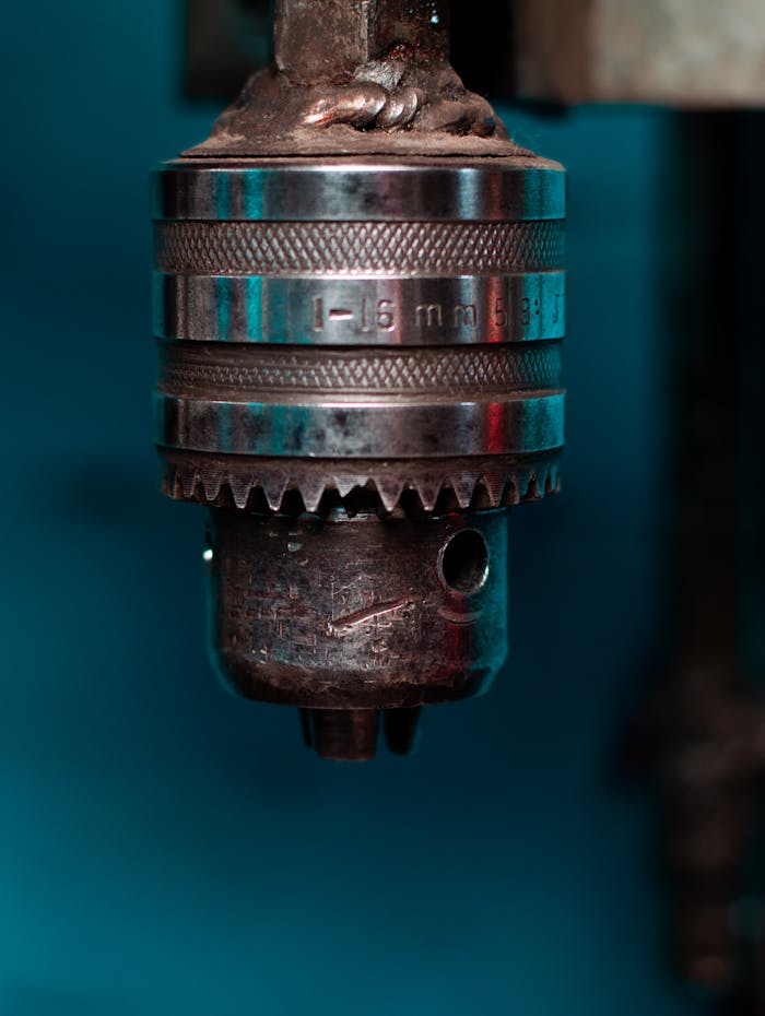 Detailed view of a metal drill chuck in a workshop setting, showcasing industrial precision.