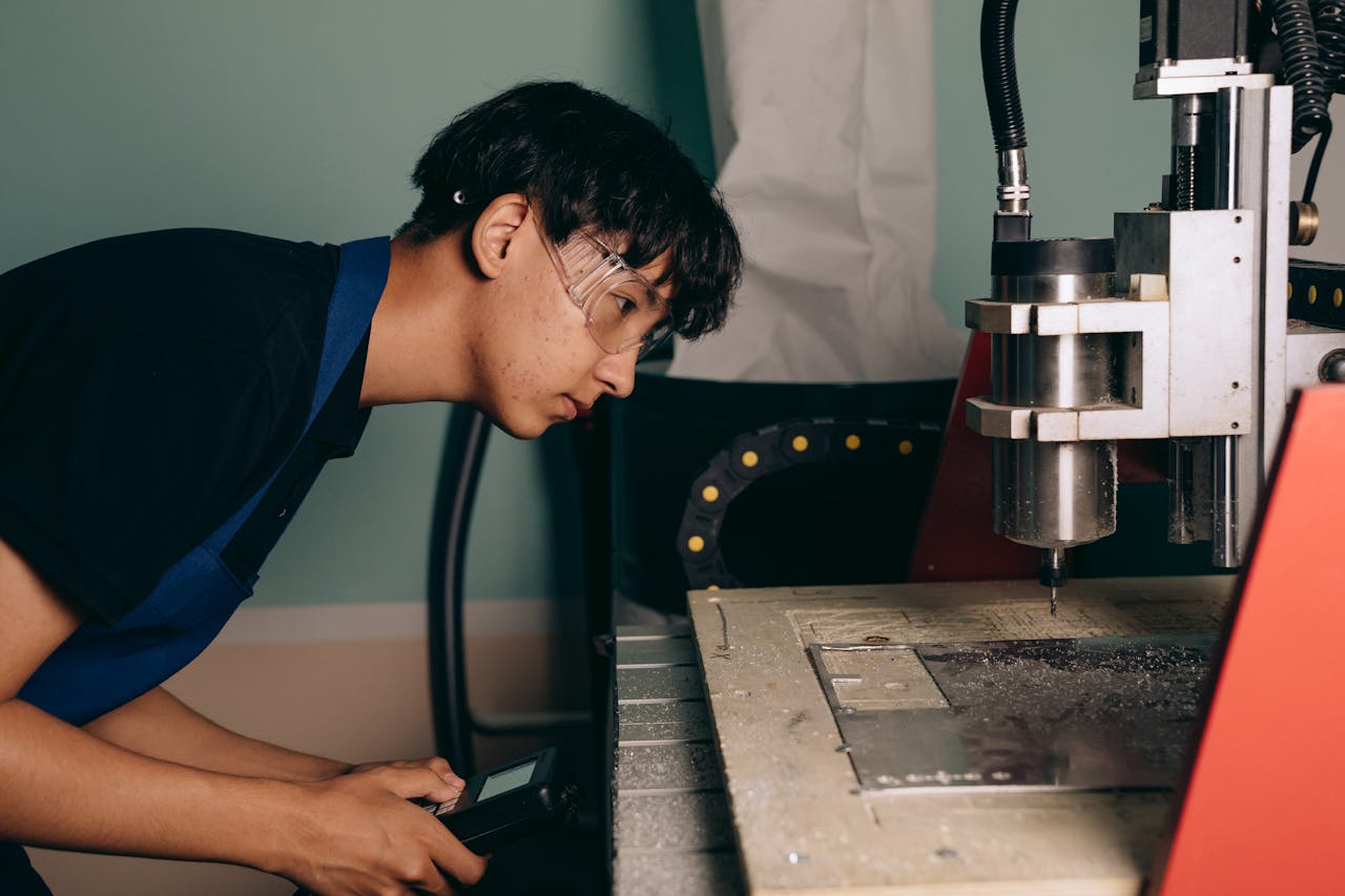 who-we-are Focused young engineer operating a CNC machine in a modern workshop setting.
